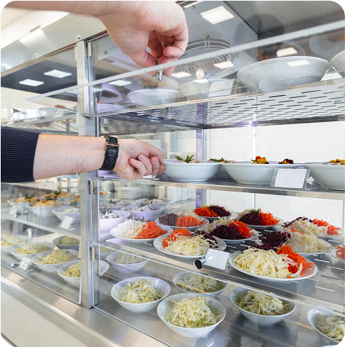 A man's hand taking fresh food from a stocked shelf.