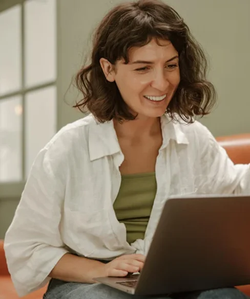 A woman smiling while looking at her laptop.