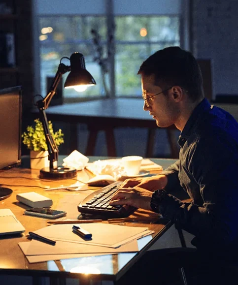 A man working on his computer in dim lighting.